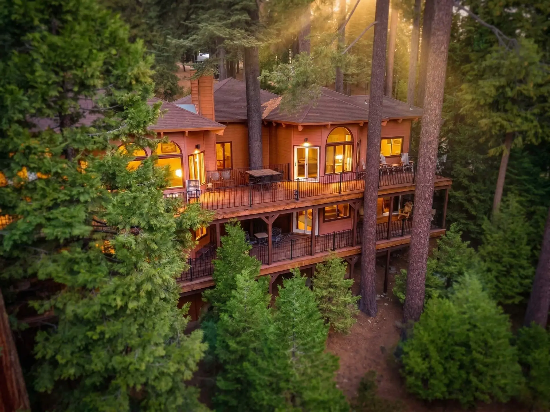 The cabin lit up among tall pines at dusk, Dardanelle Retreat